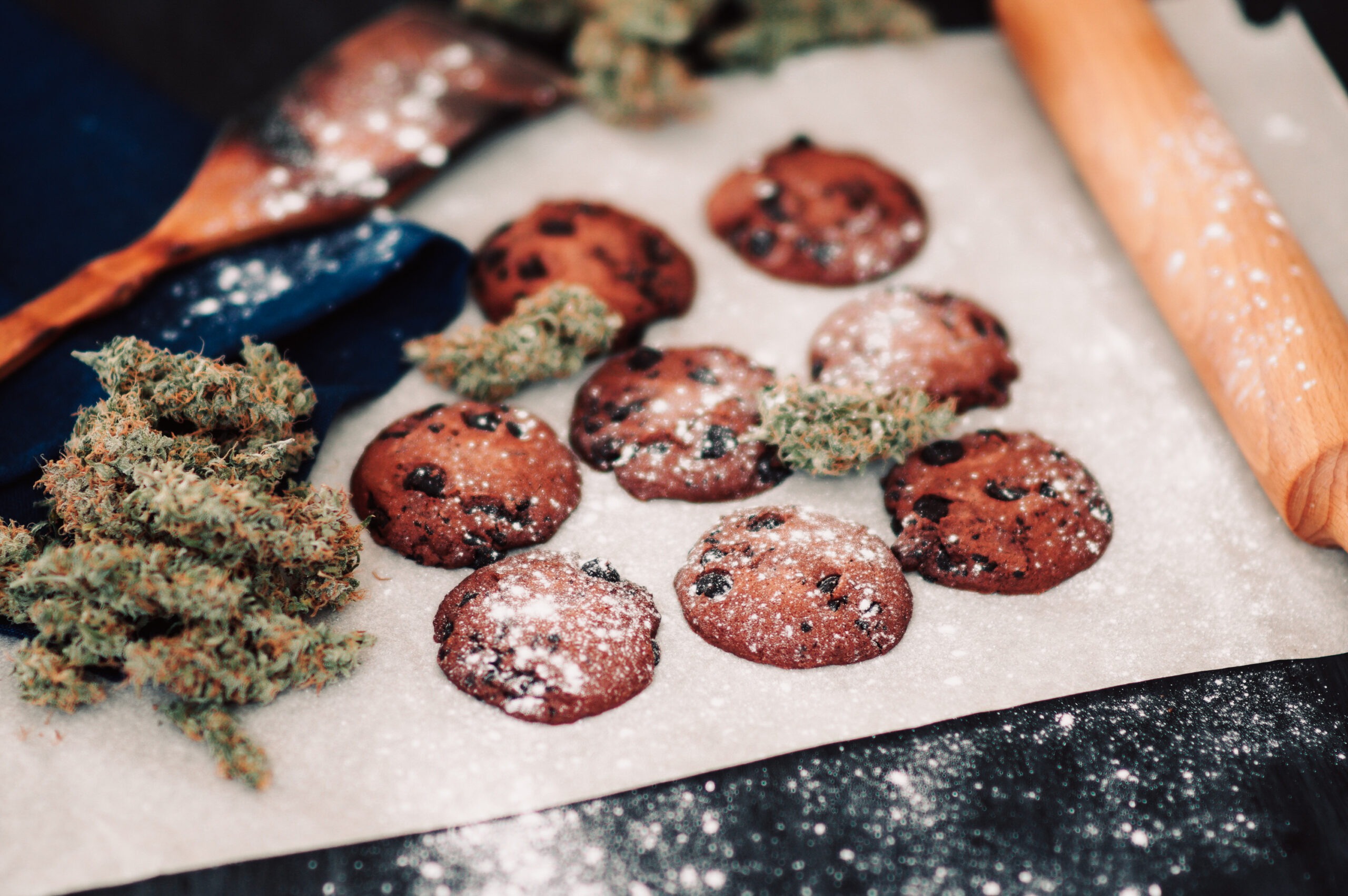 Sweets with weed. Chocolate cookies with marijuana. Sweets with cannabis. Cannabis buds on a black background. Baking with the addition of CBD.